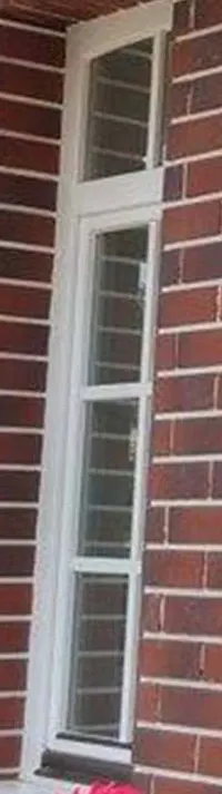 Tall narrow white wooden window with a top light and three lites in a red-brick wall