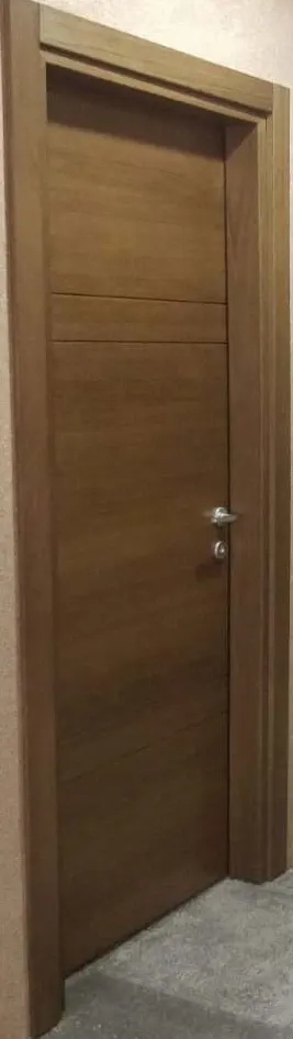 Installed brown veneered door with two pairs of grooves in a hallway, seen at an angle