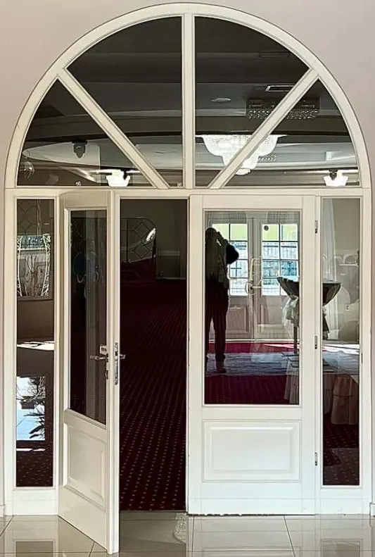 White glazed double door with narrow sidelights and a semicircular fanlight with radial bars, one leaf open